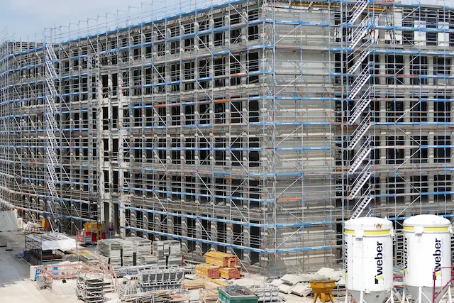 Large commercial construction site with grid scaffolding system surrounding multi-floor structure by Ontario Scaffolding